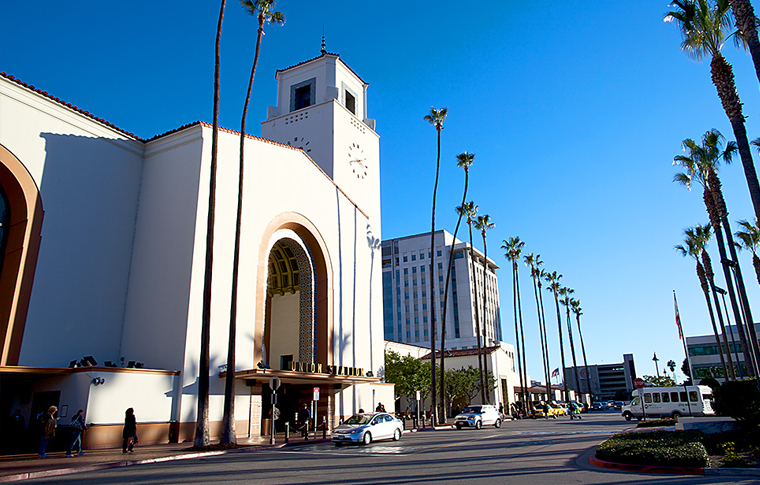 blue skies above with a white building to the left and palm trees to the right