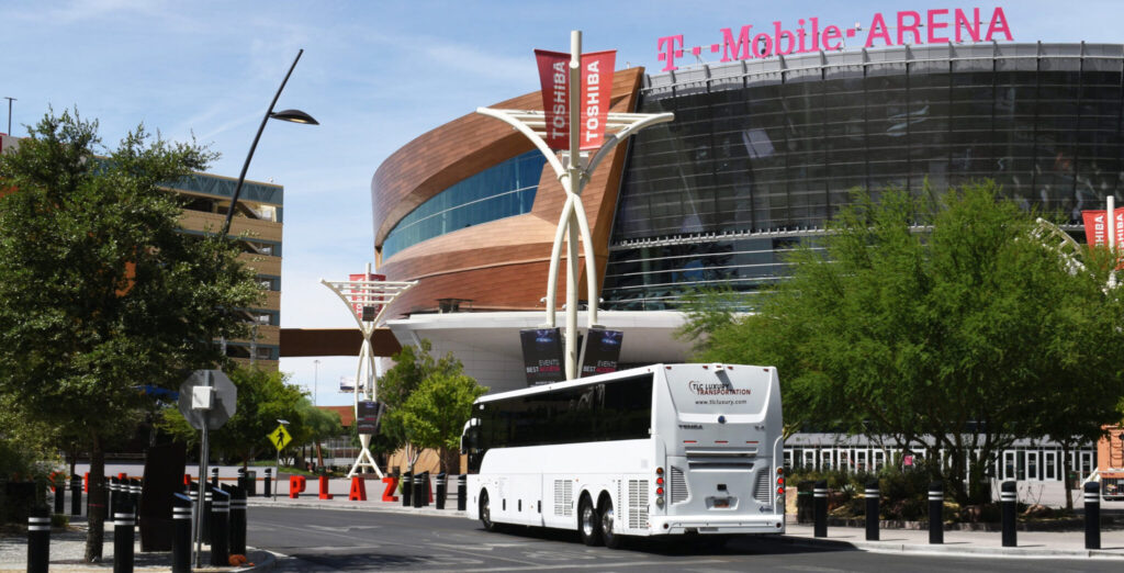 a white charter bus from TLC Luxury Transportation parked ouside T-Mobile Arena in Las Vegas