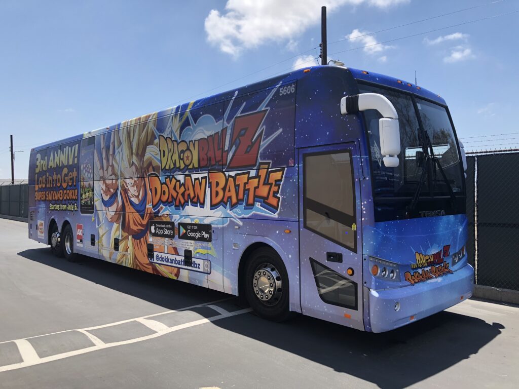 Bus parked in a parking lot with Dragon Ball Z Dokkan Battle branding on side of vehicle
