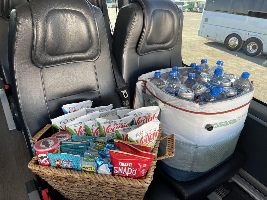 Basket of snacks and cooler filled with water bottles and cans aboard a bus